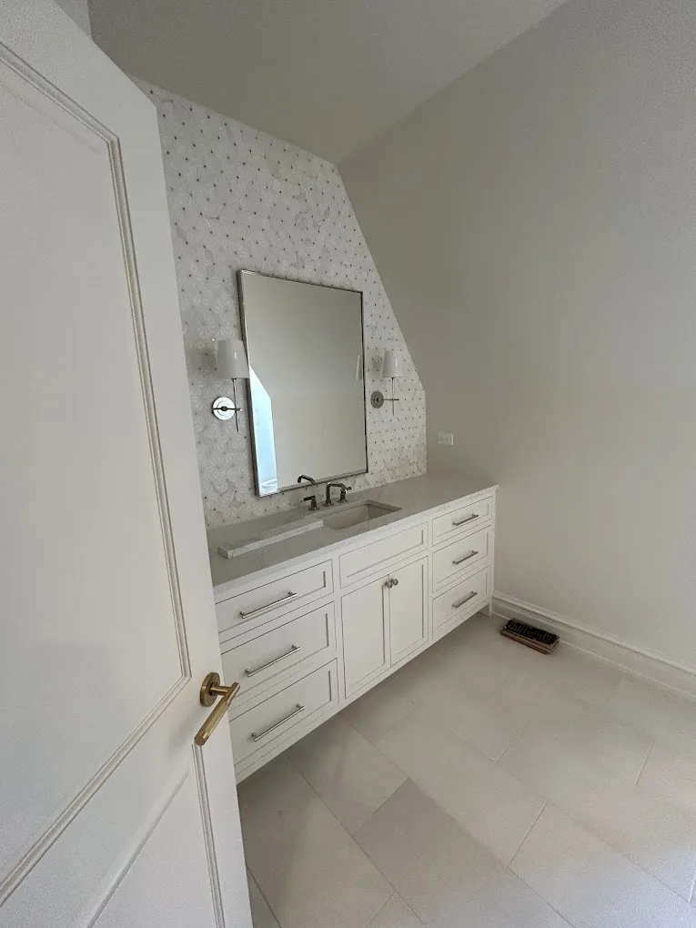 Attic bathroom vanity with marble mosaic accent wall and wall-mounted sconce