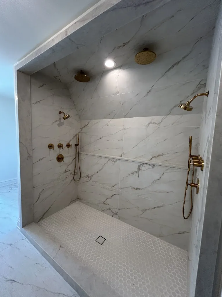 Marble shower with brass rain head, hand shower, and mosaic tile floor