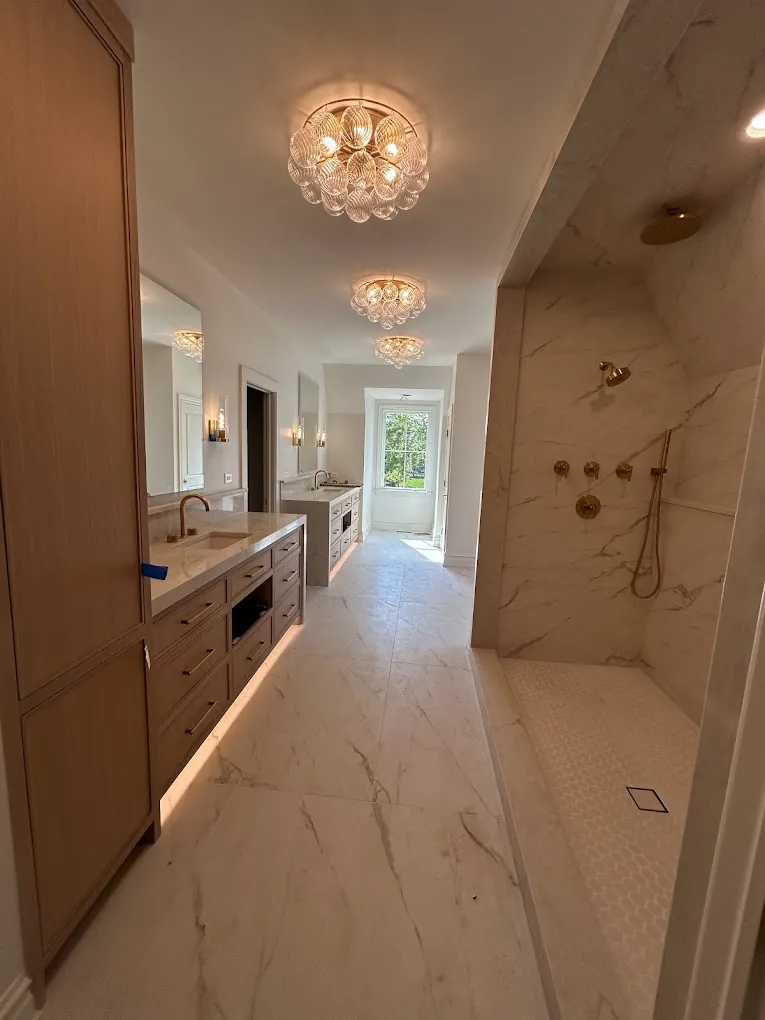 Master bath corridor with walnut vanity wall, underglow lighting, crystal chandelier, and marble floors