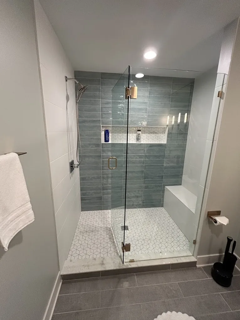 Sage-green tiled shower with frameless glass — Artigiano tile work