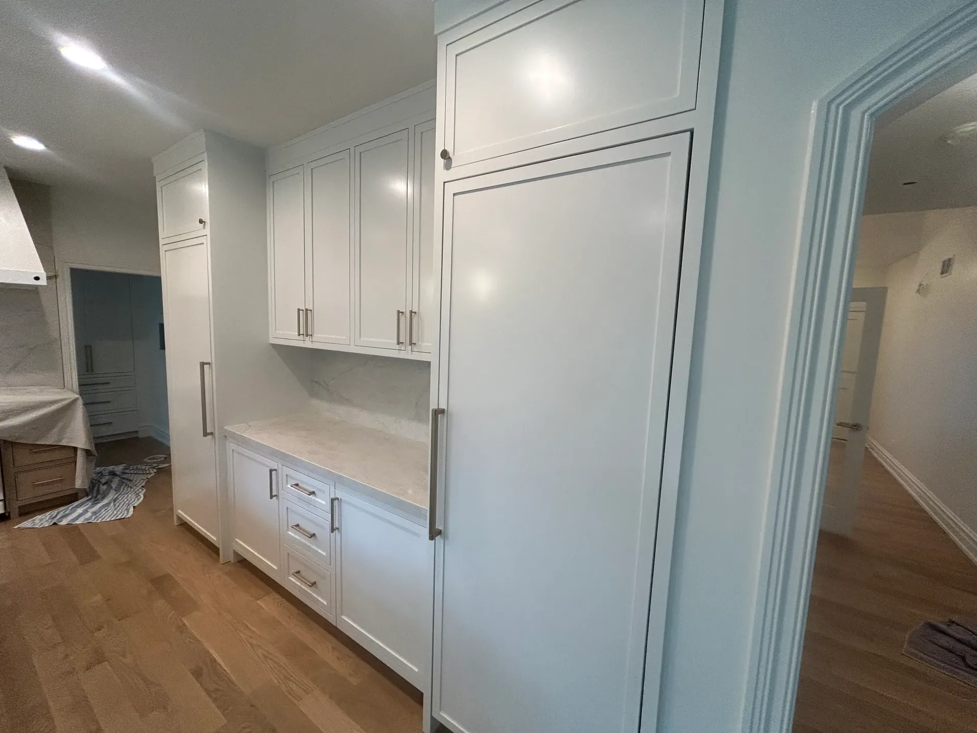 White inset-shaker kitchen cabinetry with tall pantry wall and white-oak flooring