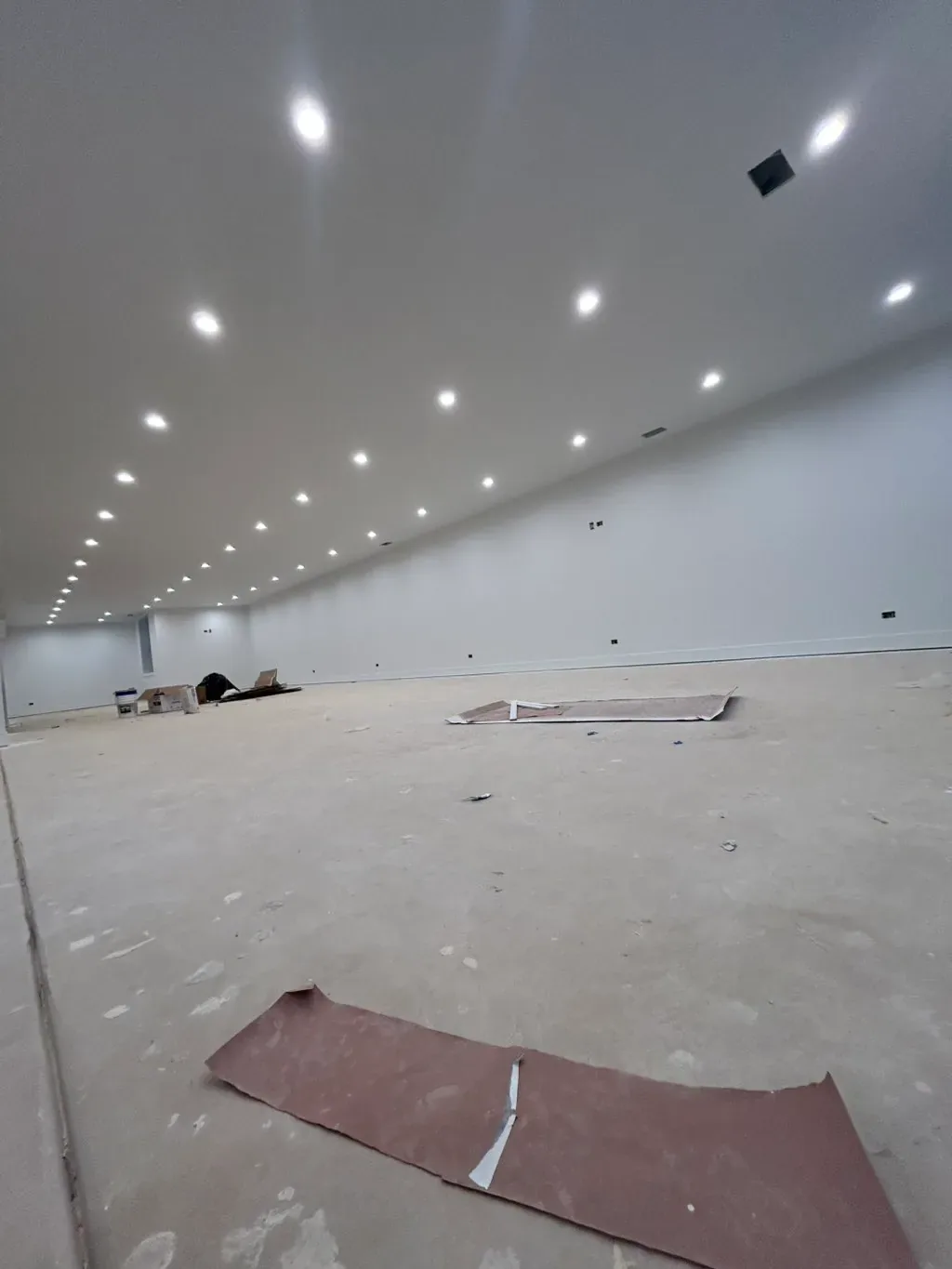 Open basement build-out primed and lit with recessed fixtures